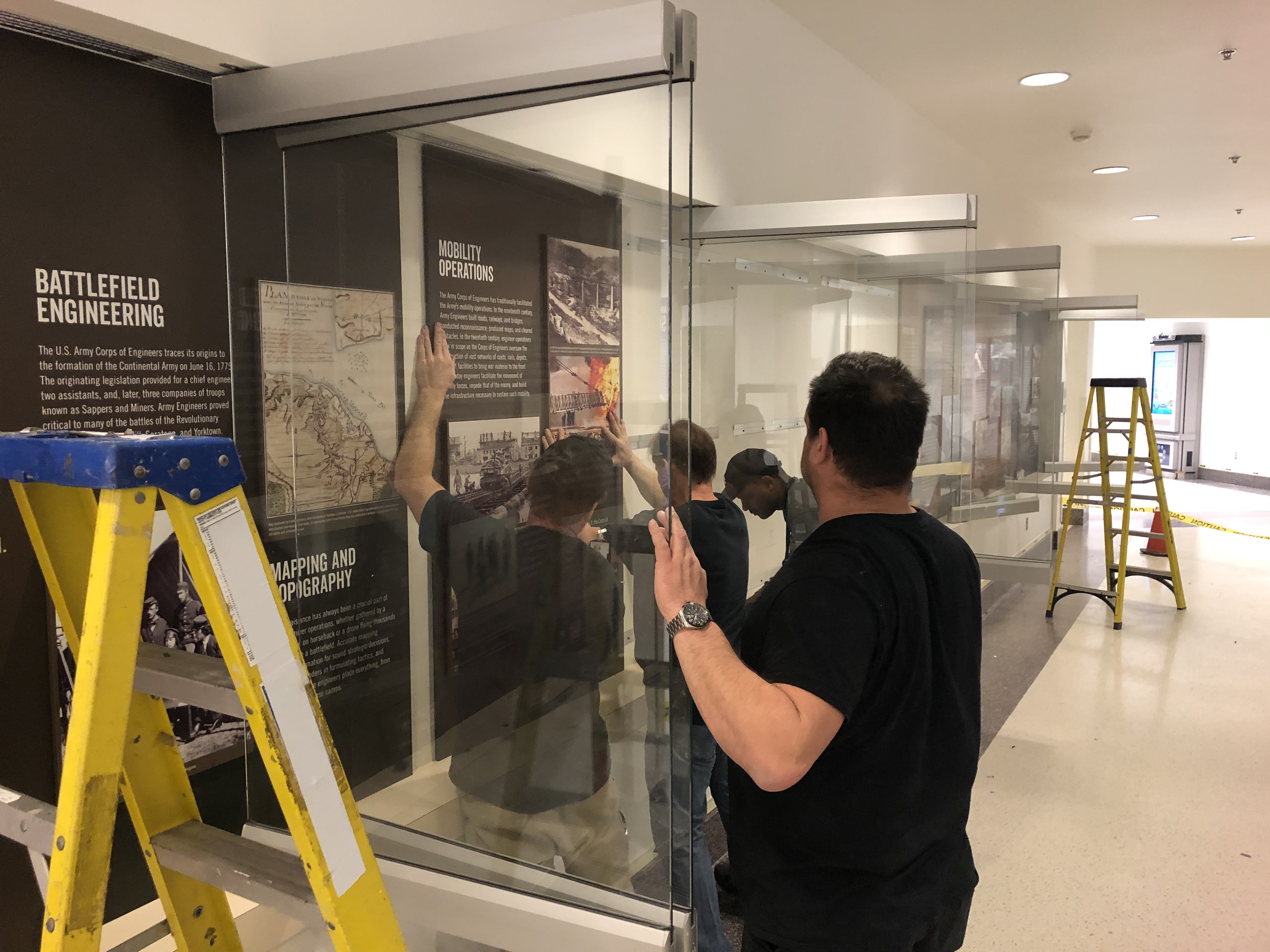 Men install panels in glass cases Men install panels in glass cases